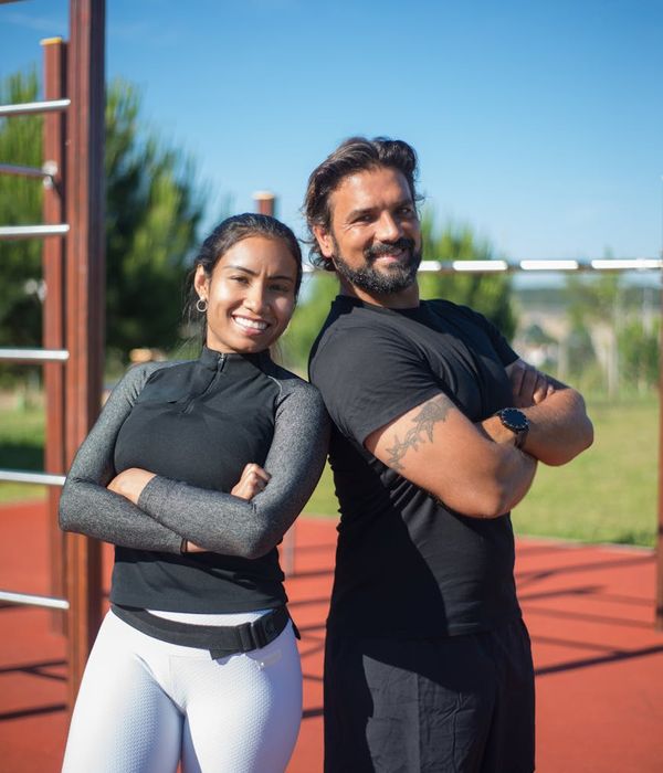 A woman in comfortable sportswear smiling outdoors in a sunny park.