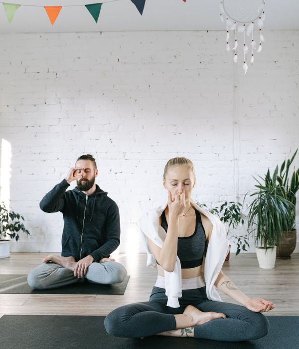 Man meditating on a yoga mat with a serene expression in a minimalist room.